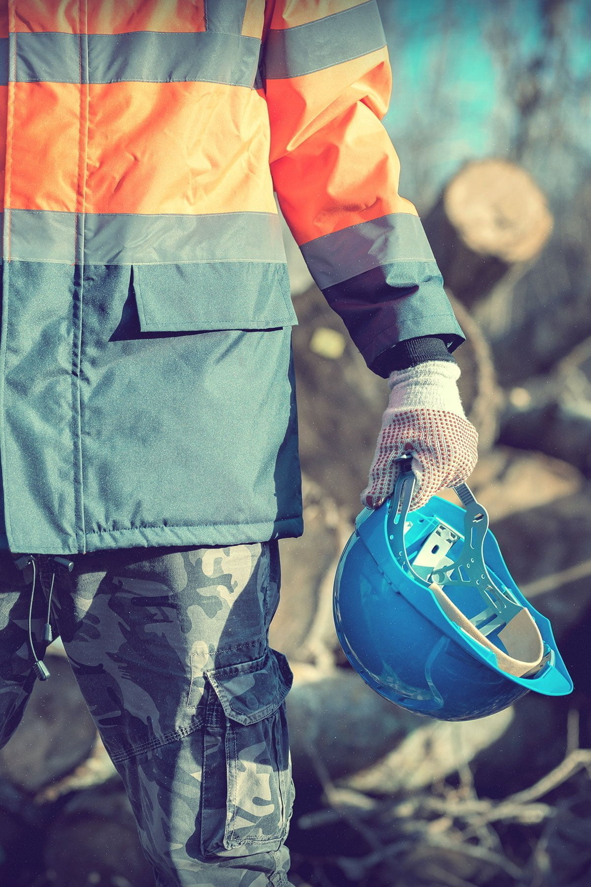Image of apprentice working in field holding safety helmet